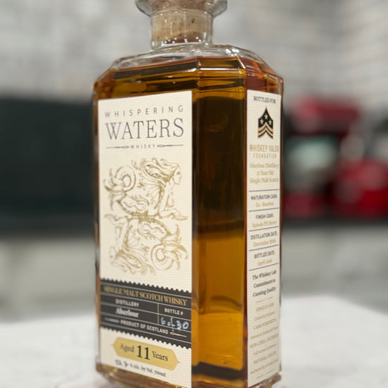 Bottle of Whispering Waters whiskey on a marble surface with a blurred background